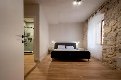 a bedroom with a bed and a stone wall at Modern Design Old Town Apartment by MN Property in Kotor