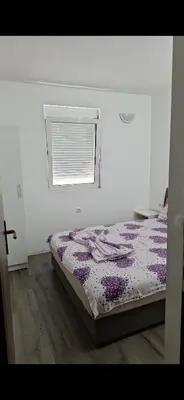 a bedroom with a bed with a purple comforter and a window at Apartmani Madžgalj Sutomore in Sutomore