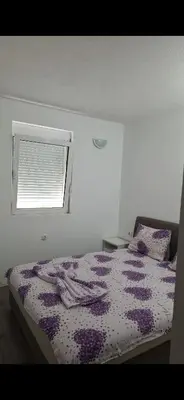 a bedroom with a bed with a purple comforter and a window at Apartmani Madžgalj Sutomore in Sutomore