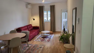 a living room with a red couch and a table at BrandNew Apartment in Podgorica