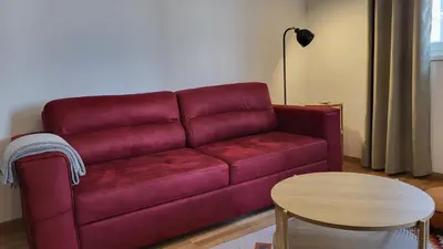 a red couch in a living room with a table at BrandNew Apartment in Podgorica