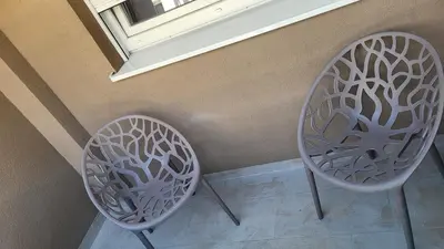 two chairs sitting next to a wall with a window at BrandNew Apartment in Podgorica