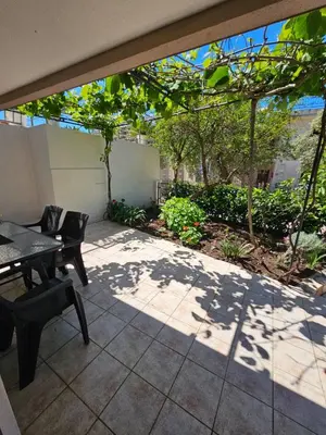 a patio with a table and chairs and trees at Vila Lučica apartman u prizemlju in Petrovac na Moru