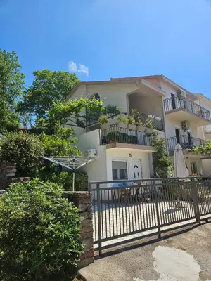 a large white building with a balcony and a fence at Vila Lučica apartman u prizemlju in Petrovac na Moru
