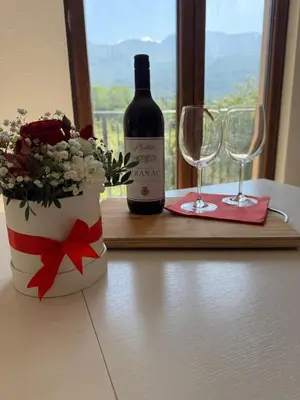 a bottle of wine and a vase with flowers and glasses at Apartments Tripoint Kotor in Kotor