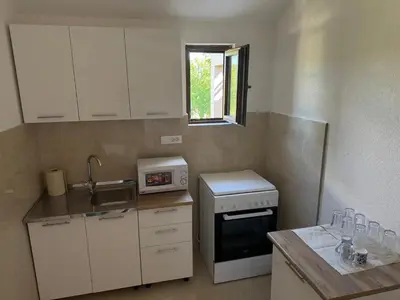 a small kitchen with white cabinets and a window at Apartments Tripoint Kotor in Kotor