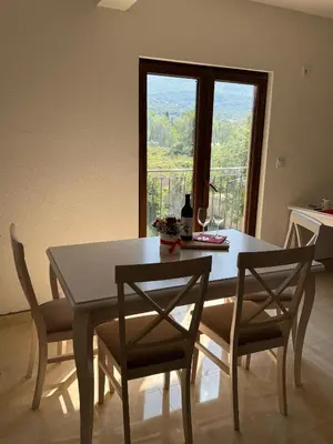 a dining room with a table and chairs and a window at Apartments Tripoint Kotor in Kotor