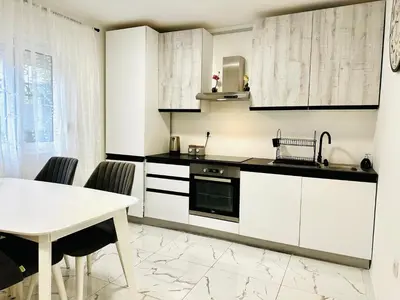 a kitchen with white cabinets and a white table at MorePlanina in Sutomore