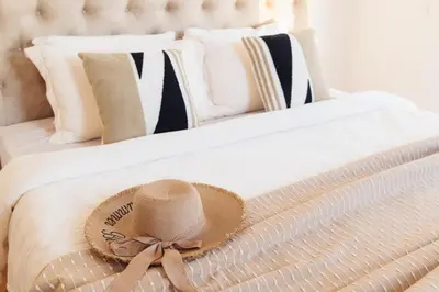 a straw hat on a bed with black and white pillows at Home of Sveti Stefan in Sveti Stefan