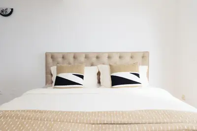 a white bed with black and white pillows on it at Home of Sveti Stefan in Sveti Stefan