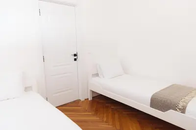 a white bedroom with two beds and a door at Home of Sveti Stefan in Sveti Stefan