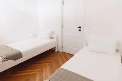 two beds in a room with white walls and wooden floors at Home of Sveti Stefan in Sveti Stefan
