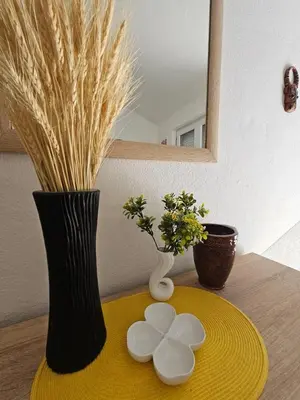 a table with a black vase and a yellow plate with flowers at Vila Lučica apartman 2 pogled planina in Petrovac na Moru