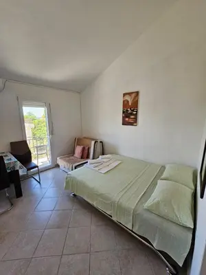 a bedroom with a bed and a chair and a window at Vila Lučica studio pogled na more in Petrovac na Moru