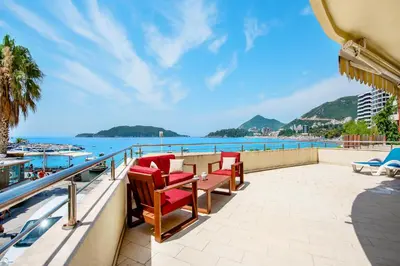 a balcony with a table and chairs and the ocean at Luxury Apartments Rafailovichi 1 st of the sea line in Rafailovici