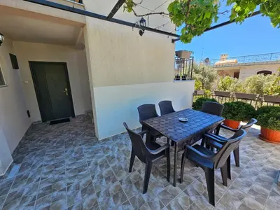 a patio with a table and chairs on a patio at Vila Lučica apartman pogled na more in Petrovac na Moru