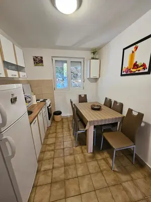 a kitchen and dining room with a table and a refrigerator at Vila Lučica apartman pogled na more in Petrovac na Moru