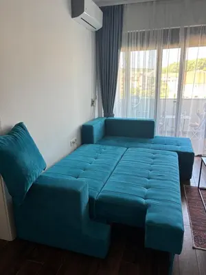 a blue couch in a room with a window at Apartman Sofija in Ulcinj
