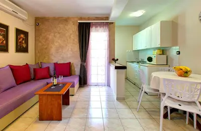 a living room with a purple couch and a kitchen at Vila Koral in Petrovac na Moru