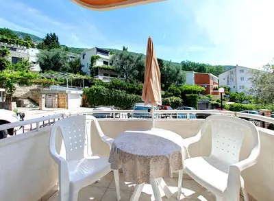 a table and chairs on a balcony with an umbrella at Vila Koral in Petrovac na Moru