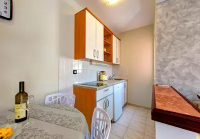 a small kitchen with a table and a bottle of wine at Vila Koral in Petrovac na Moru