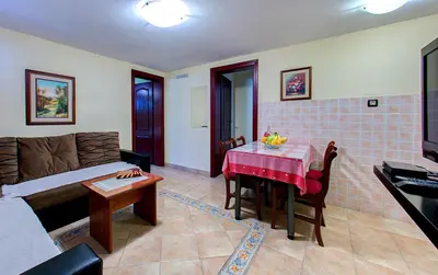 a living room with a bed and a table with a red tableablish at Vila Koral in Petrovac na Moru