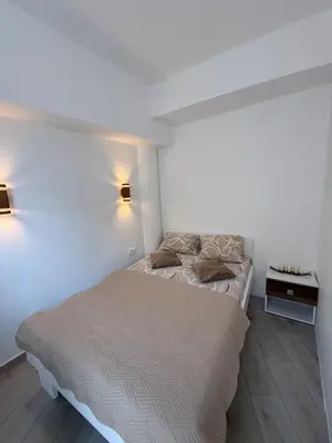 a white bedroom with a bed and a side table at Morski kutak in Sutomore