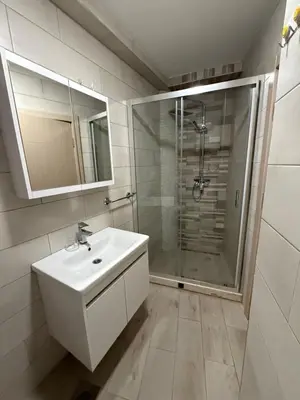 a white bathroom with a shower and a sink at Morski kutak in Sutomore