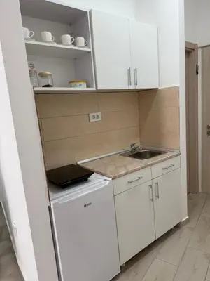 a small kitchen with white cabinets and a sink at Morski kutak in Sutomore