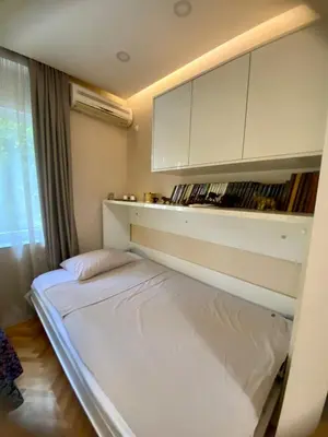 a bedroom with a bed and a shelf with books at City Center 1 in Podgorica