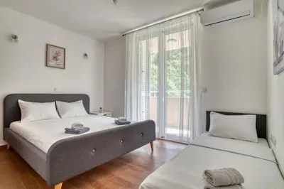 a bedroom with two beds and a large window at Sea Elegance Rafailovici in Rafailovici