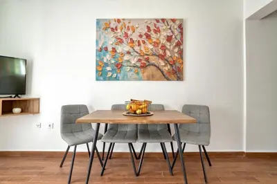 a dining room table with chairs and a painting at Sea Elegance Rafailovici in Rafailovici
