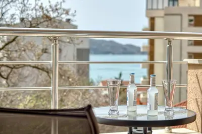 a table with two bottles and glasses on a balcony at Sea Elegance Rafailovici in Rafailovici