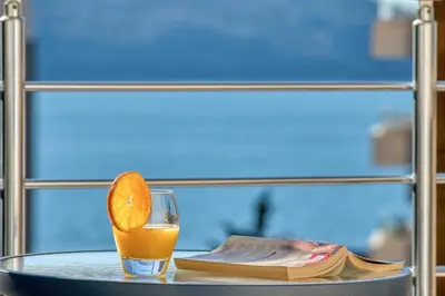 a glass of orange juice sitting on a table with a book at Seabreeze Rafailovici in Rafailovici