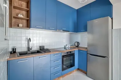 a kitchen with blue cabinets and a stainless steel refrigerator at Seabreeze Rafailovici in Rafailovici
