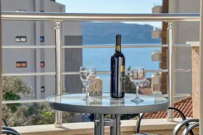 a bottle of wine and two glasses on a table on a balcony at Seabreeze Rafailovici in Rafailovici
