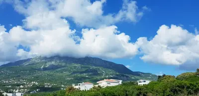 a view of a mountain with clouds in the sky at Emerald Dreamscape with Private Beach & Pool in Dobra Voda