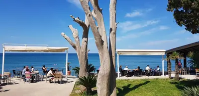 a group of people sitting at tables near the ocean at Emerald Dreamscape with Private Beach & Pool in Dobra Voda