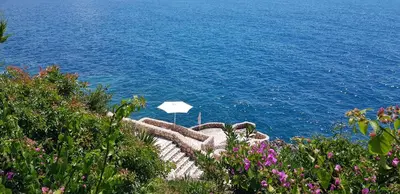 an umbrella sitting on the side of the water at Emerald Dreamscape with Private Beach & Pool in Dobra Voda