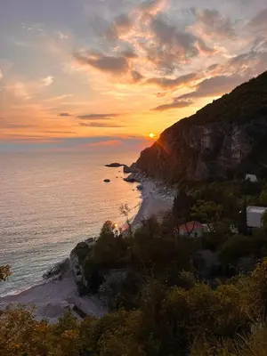 a sunset over a beach with the ocean and a mountain at La Lumiere Perazica Do in Perazića Do