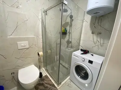 a bathroom with a shower and a washing machine at Apartament Adian in Ulcinj