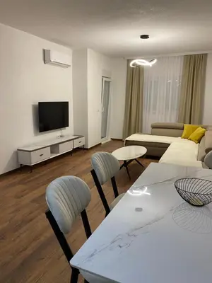 a living room with a couch and a table and chairs at Apartament Adian in Ulcinj