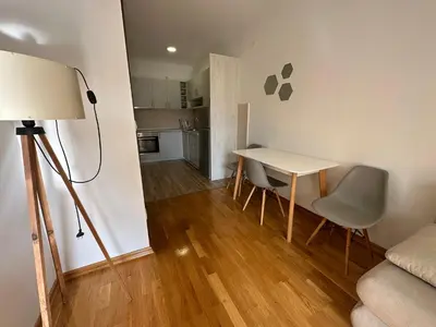 a living room with a table and chairs and a kitchen at Apartment ViSi 101 in Budva
