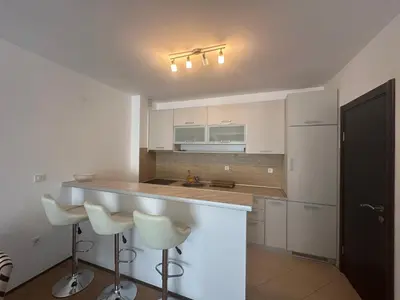 a kitchen with white cabinets and a counter with stools at Apartment ViSI 102 in Budva
