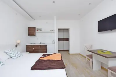 a bedroom with a bed and a desk and a kitchen at Apartments Ivanovic in Budva