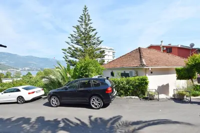 two cars parked in a parking lot in front of a house at Apartments Ivanovic in Budva