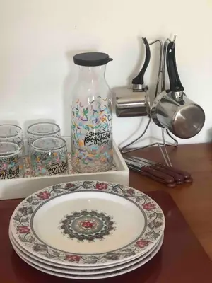 a plate on a table with a glass jar and a vase at NIDA Apartment in Ulcinj