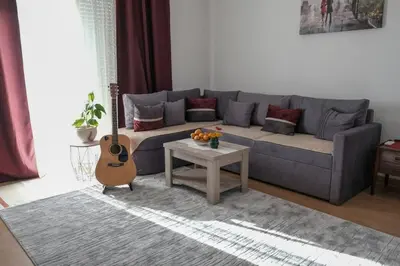 a living room with a blue couch and a guitar at NIDA Apartment in Ulcinj