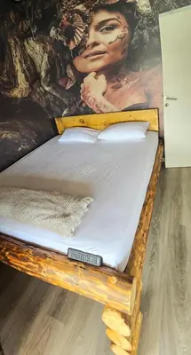 a wooden bed with a painting on the wall at River house Una in Kravlja