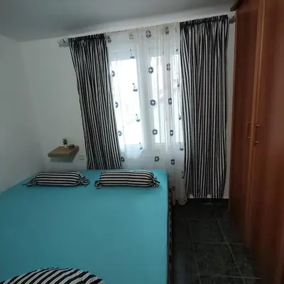a bedroom with a blue bed with black and white curtains at Holiday home Sutomore in Sutomore